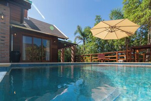 Una piscina con cubierta de madera y un pérgola.