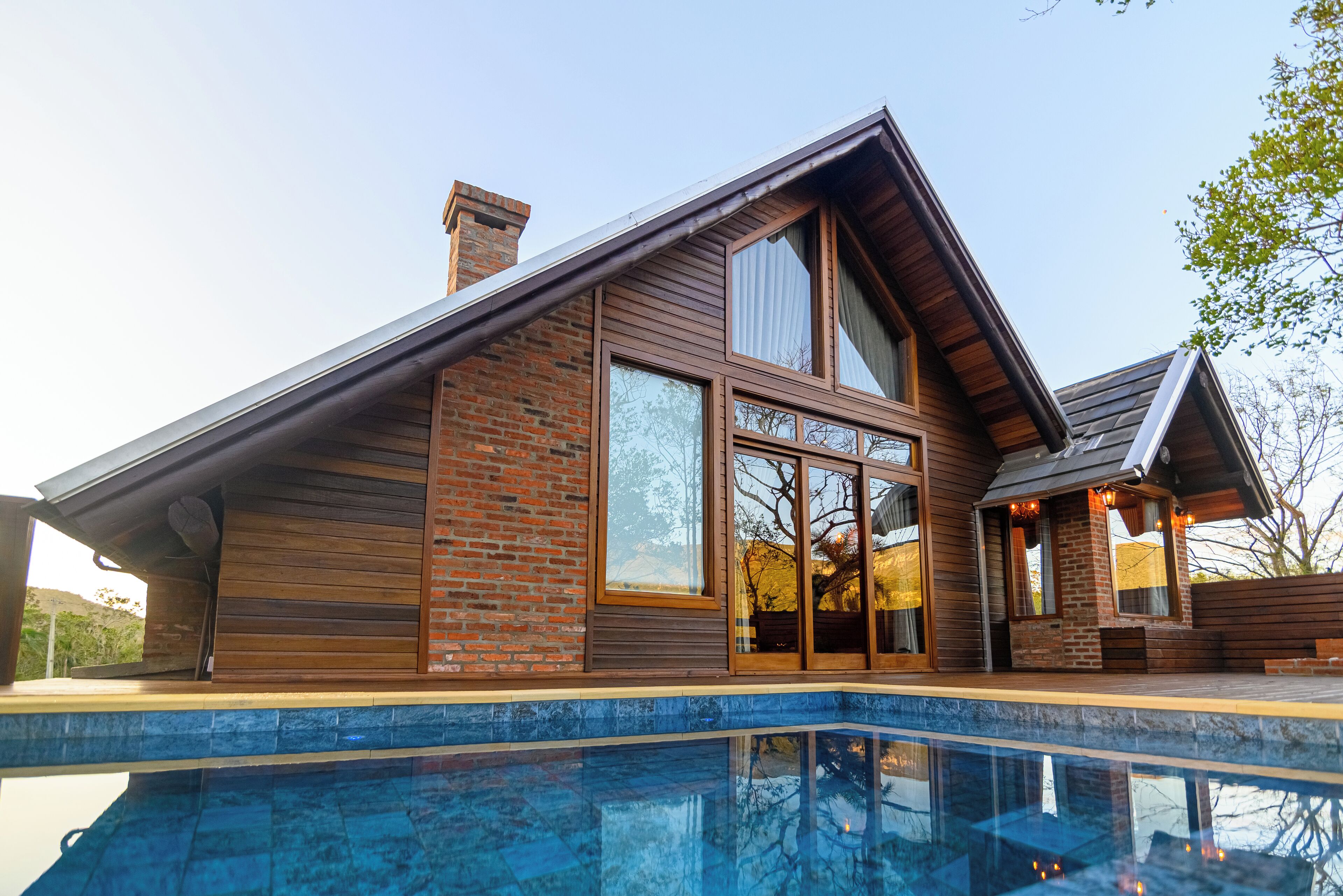 A modern house with a large glass window, a brick exterior, and a swimming pool.