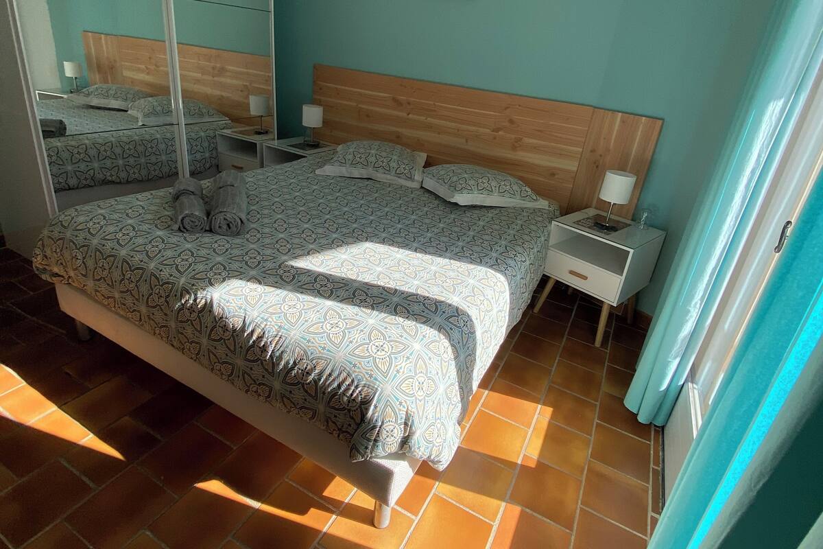 Une chambre à coucher avec un grand lit, une table de chevet, un miroir et un tableau au mur.