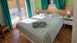 Ein Schlafzimmer mit Bett, Nachttisch, Lampe und Blick ins Freie durch eine Schiebetür.
