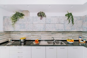 A modern kitchen with a granite backsplash, stainless steel sink, and white cabinets.