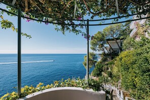 A coastal view with a pergola and lush greenery overlooking the sea.