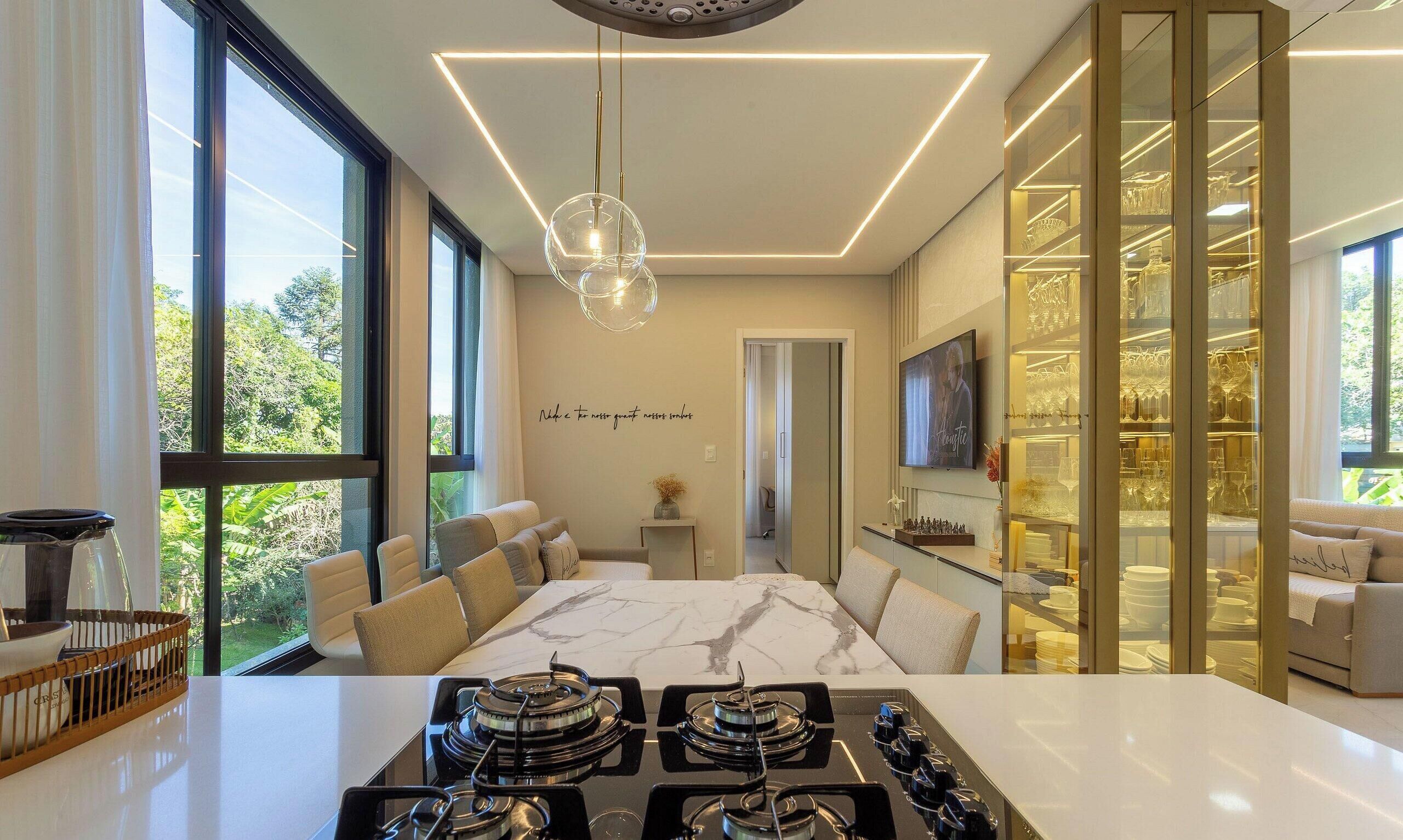 A modern kitchen with a central island, a dining area with a marble table, and a glass-fronted display cabinet.