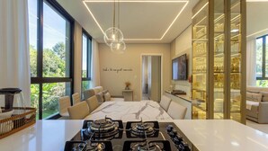 Une cuisine moderne dotée d’un îlot central, d’un coin repas avec une table en marbre et d’un meuble vitrine à façade en verre.