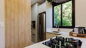 Une cuisine moderne dotée d’une cuisinière à gaz intégrée, d’appareils électroménagers en acier inoxydable et d’une fenêtre donnant sur un paysage verdoyant.