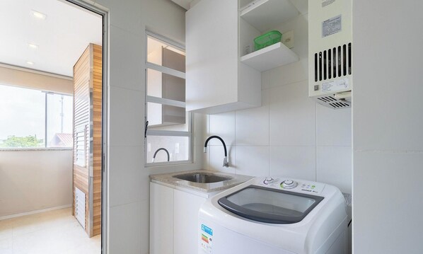 A compact kitchen with a built-in washing machine, a sink, and a window. - Apartments With Pool in Floripa - CAC (Florianópolis)
