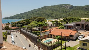 Ein Wohngebiet mit Schwimmbad, einer Straße mit parkenden Autos und Blick auf Meer und Hügel.