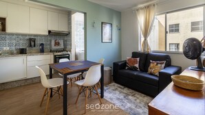 A compact living space with a kitchenette, dining area, and a sofa with a view of the city. - Condominium in Floripa 300m From the Beach - CAS (Florianópolis)