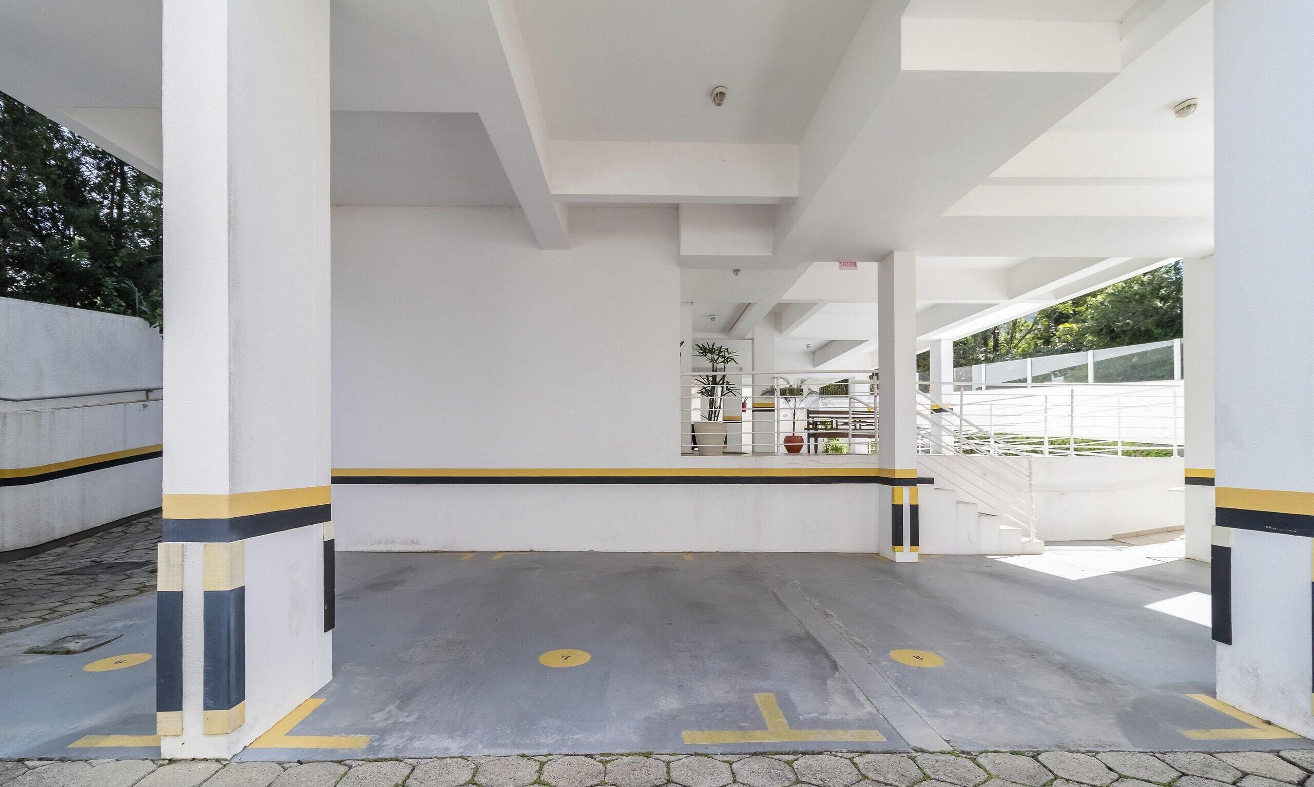 A parking area with white pillars, yellow and black stripes, and a clear path marked with arrows.