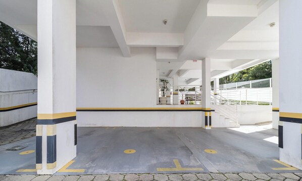 A parking area with white pillars, yellow and black stripes, and a clear path marked with arrows. - Apt w/ Barbecue Near the Beach in Campeche Bve101 (Florianópolis)