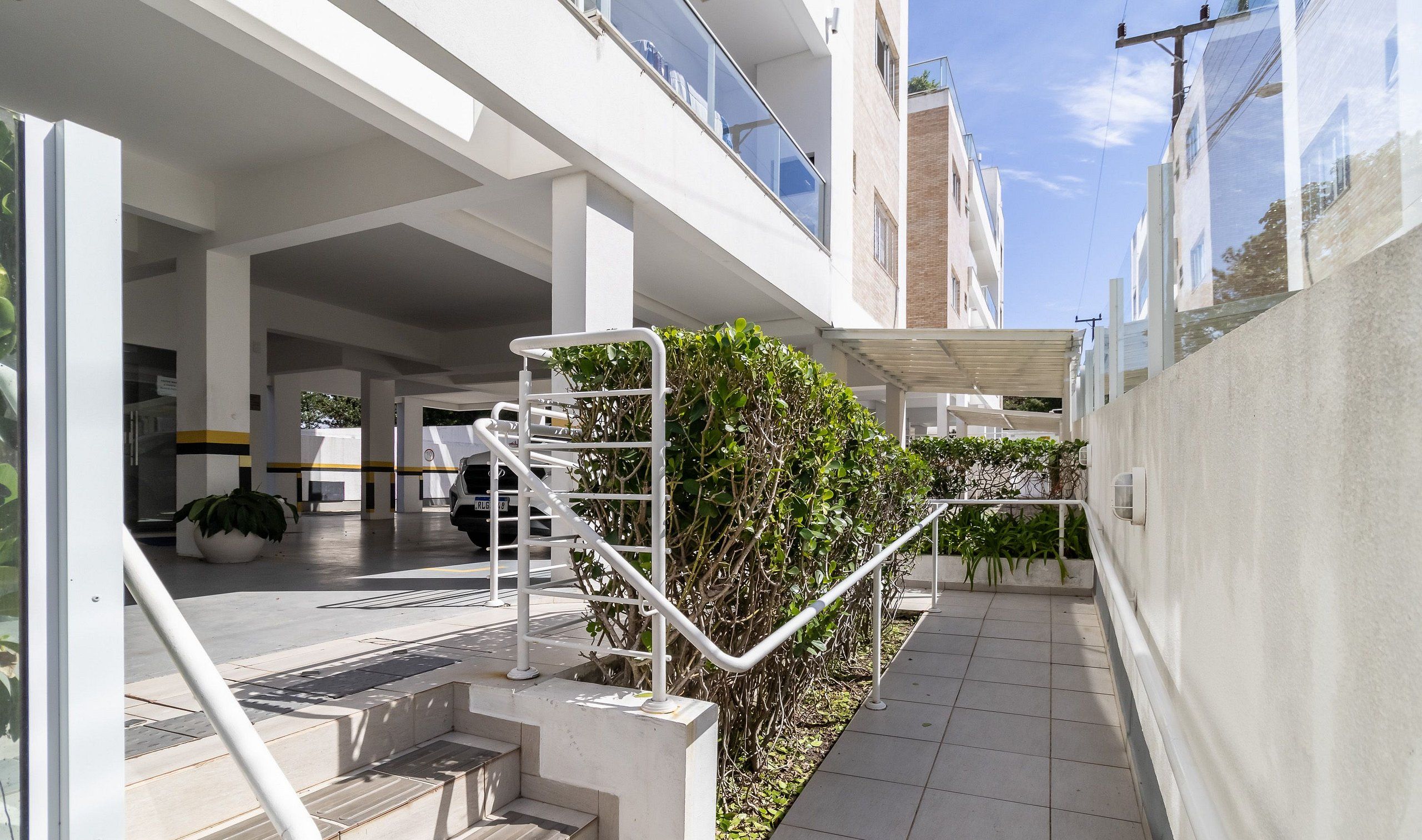 Un edificio moderno con un área exterior cubierta, una escalera y un vehículo estacionado en su interior.