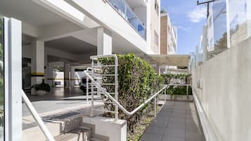 Un edificio moderno con un área exterior cubierta, una escalera y un vehículo estacionado en su interior.