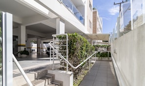 A modern building with a covered outdoor area, a staircase, and a vehicle parked inside.