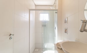 A modern bathroom with a glass-enclosed shower, a large white sink, and a toilet.