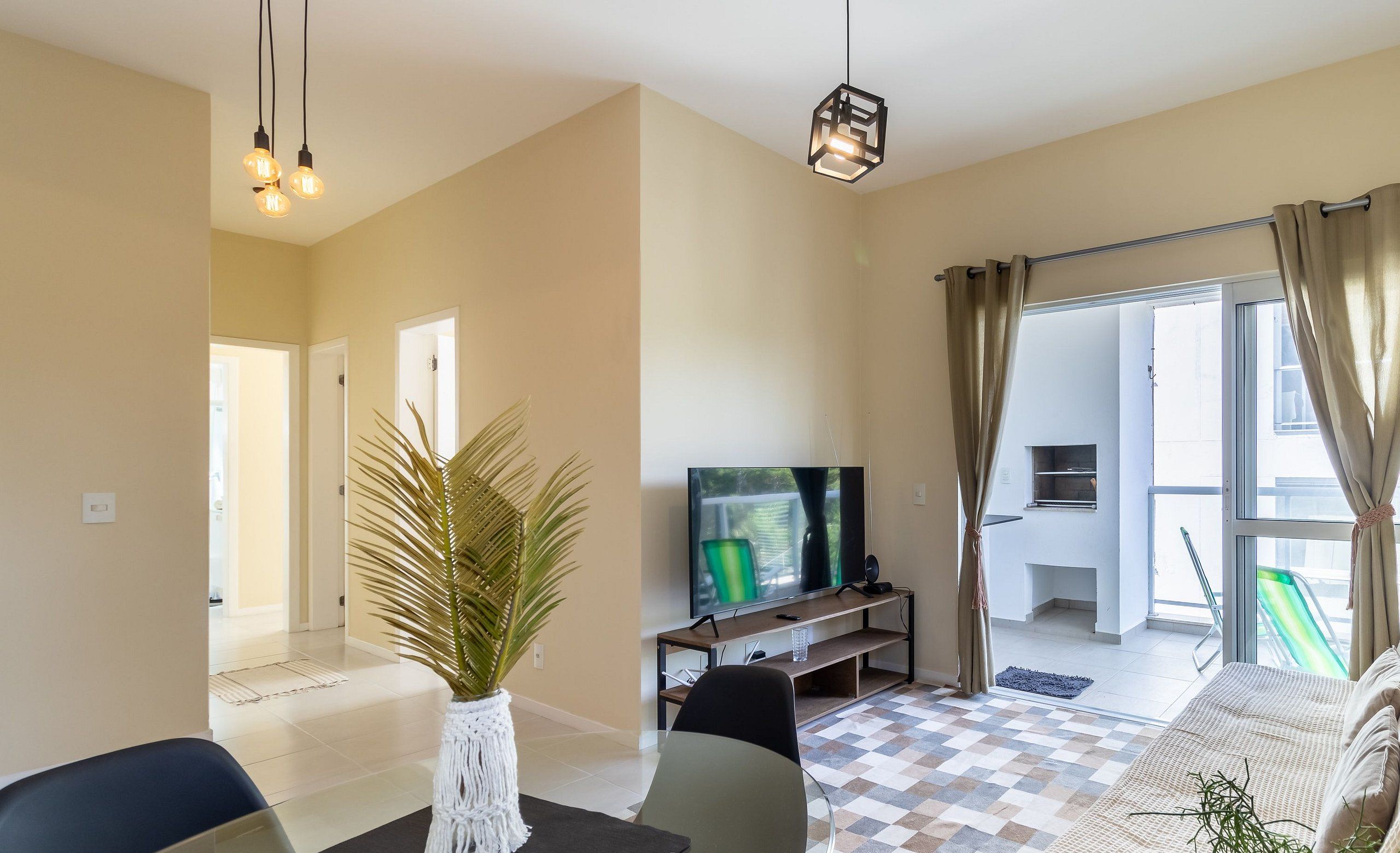 Una sala de estar moderna con televisor, zona de estar y vistas al exterior.