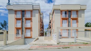 A residential building with multiple balconies, a gated entrance, and a clear sky.