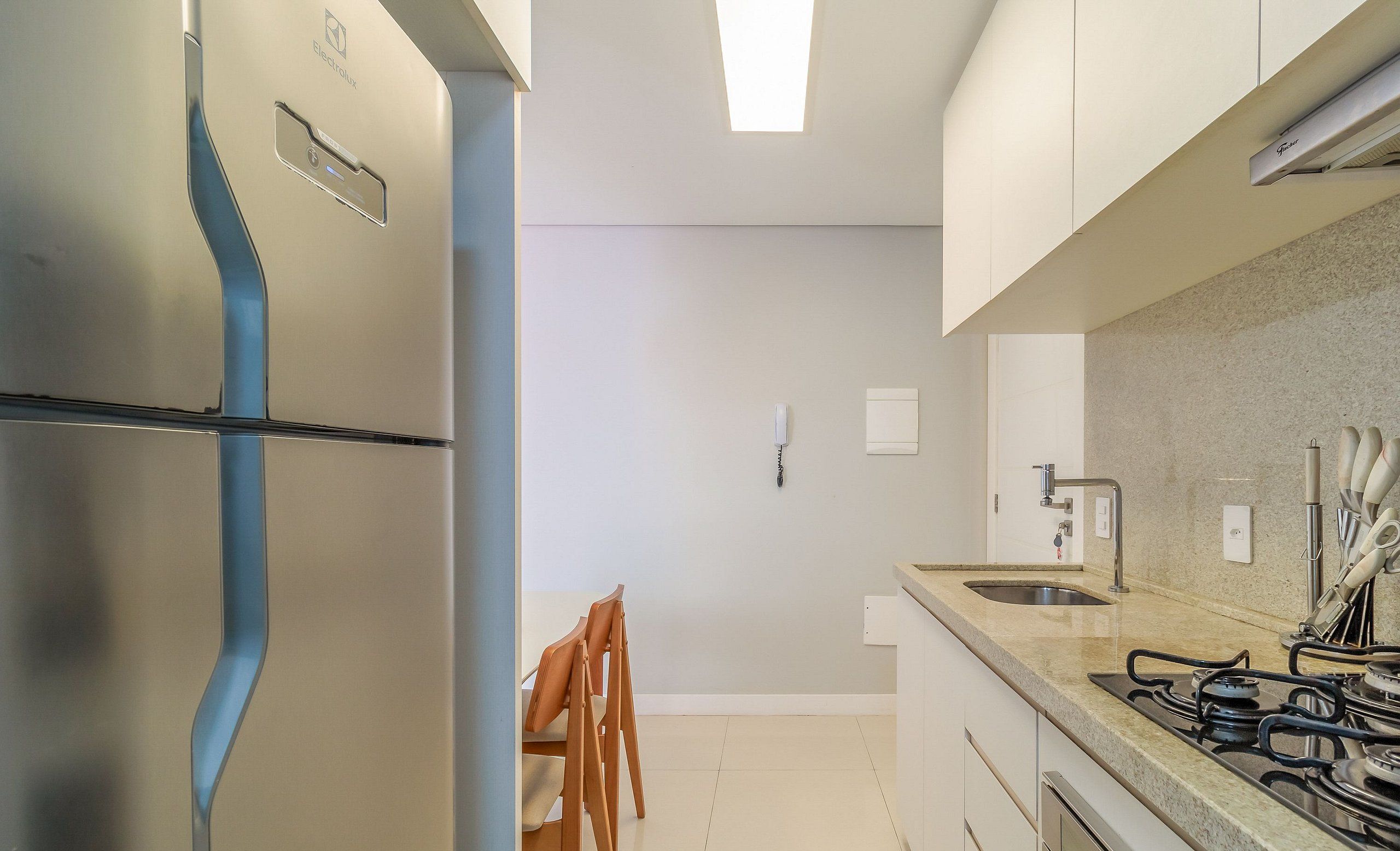 Una cocina moderna con refrigerador empotrado, estufa a gas y pileta.