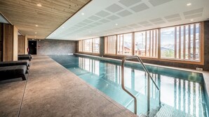 A swimming pool with a wooden ceiling and large windows.