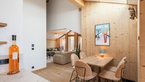 A modern interior with a wooden dining area, a sofa, and a poster on the wall.