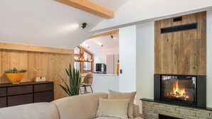 A modern living room with a fireplace, wooden ceiling beams, and a cozy sofa.