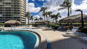 A resort pool area with a large pool, lounge chairs, and palm trees. - South Seas Tower II, 1701 (Marco Island)