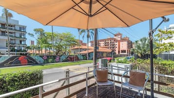 An outdoor seating area with a large umbrella, metal chairs, and a view of a building with a mural.