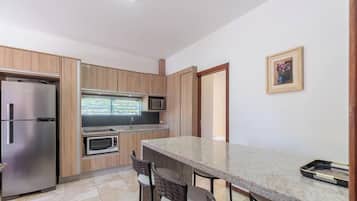 A modern kitchen with built-in appliances, a dining area with chairs, and a framed picture on the wall.
