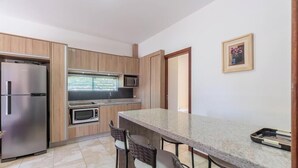A compact kitchen with a refrigerator, microwave, and a small dining area with chairs.