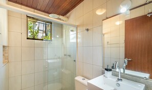 Une salle de bain moderne avec une douche à parois de verre, des toilettes, un lavabo avec un miroir et un plafond en bois.