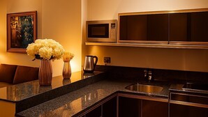 Una cocina moderna con armarios oscuros, encimera de granito, pileta de acero inoxidable, microondas y un florero con flores.