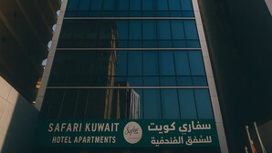 Un edificio moderno con un letrero que dice "SAFARI KUWAIT HOTEL APARTMENTS" y texto en árabe.
