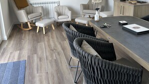 A modern dining area with a wooden table, grey upholstered chairs, and a grey rug. - Riverside Exclusive Retreat (Newquay)