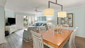 Un amplio salón con una mesa de comedor, sillas, sofá y televisor.