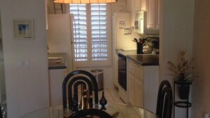 A compact kitchen with a dining area, featuring a glass table, chairs, and a hanging light fixture. - Palm Springs 2 bed/2bath condo - Great Location / Resort like setting - 2 pools (Palm Springs)