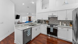 A modern kitchen with white cabinetry, a built-in oven, and a stainless steel refrigerator.