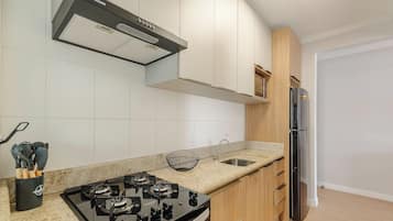 A modern kitchen with a gas stove, stainless steel refrigerator, and wooden cabinets.