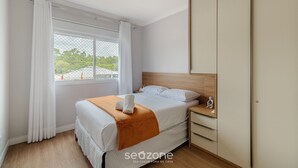 A bedroom with a bed, a nightstand, a wardrobe, and a window with curtains. - Charming apt Just 350m From the Beach! - Vgn0102 (Florianópolis)