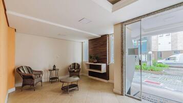 A hotel lobby with a seating area, a fireplace, and a view of the street.