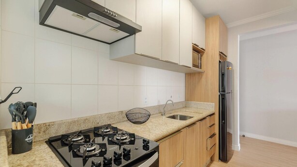 Una cocina moderna con estufa a gas, electrodomésticos de acero inoxidable y armarios de colores claros.