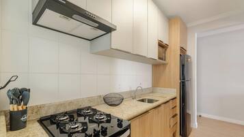 Een moderne keuken met een gasfornuis, roestvrijstalen apparatuur en lichtgekleurde kastjes.