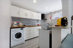 A compact kitchen with a washing machine, microwave, and a small refrigerator.