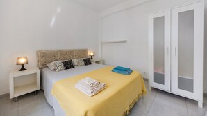 Una camera da letto con un letto, comodini, un armadio e una lampada a sospensione.