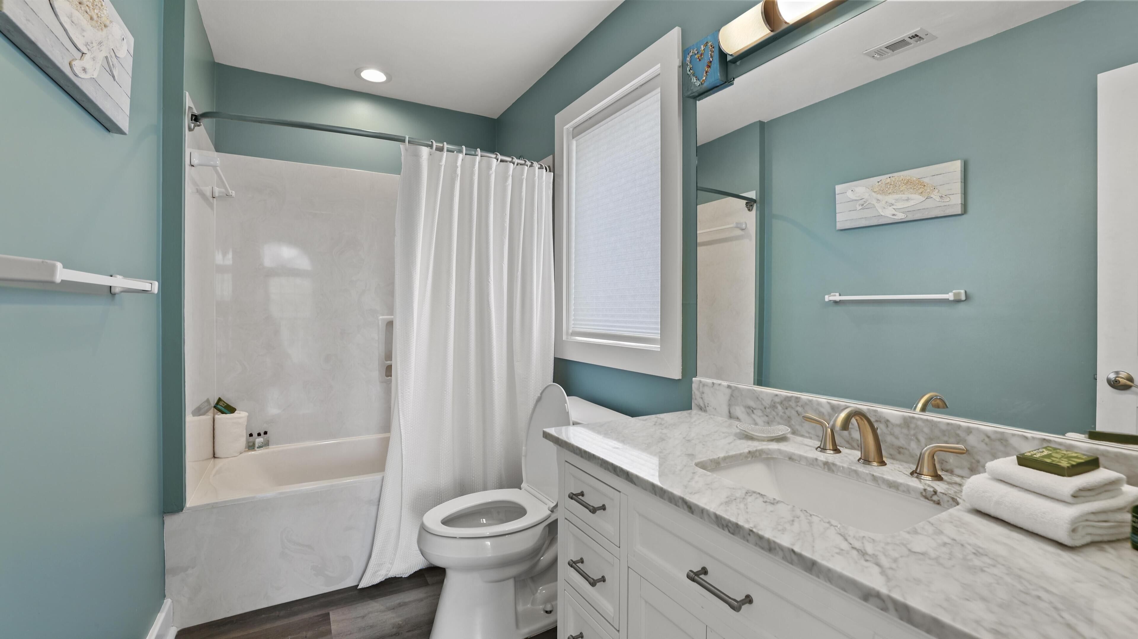 Une salle de bain équipée d’une baignoire, de toilettes et d’un meuble-lavabo avec un évier et un miroir.