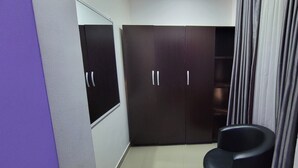 Habitació amb armari, cadira i cortina.