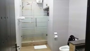 Un bany modern amb plat de dutxa de vidre, vàter i rentatge.