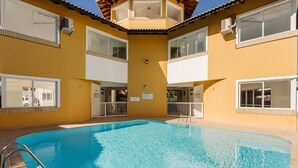 A pool area with a clear blue pool, white railings, and a yellow building facade. - House in Condo w/ Pool, 300m From the Beach Ali024 (Florianópolis)