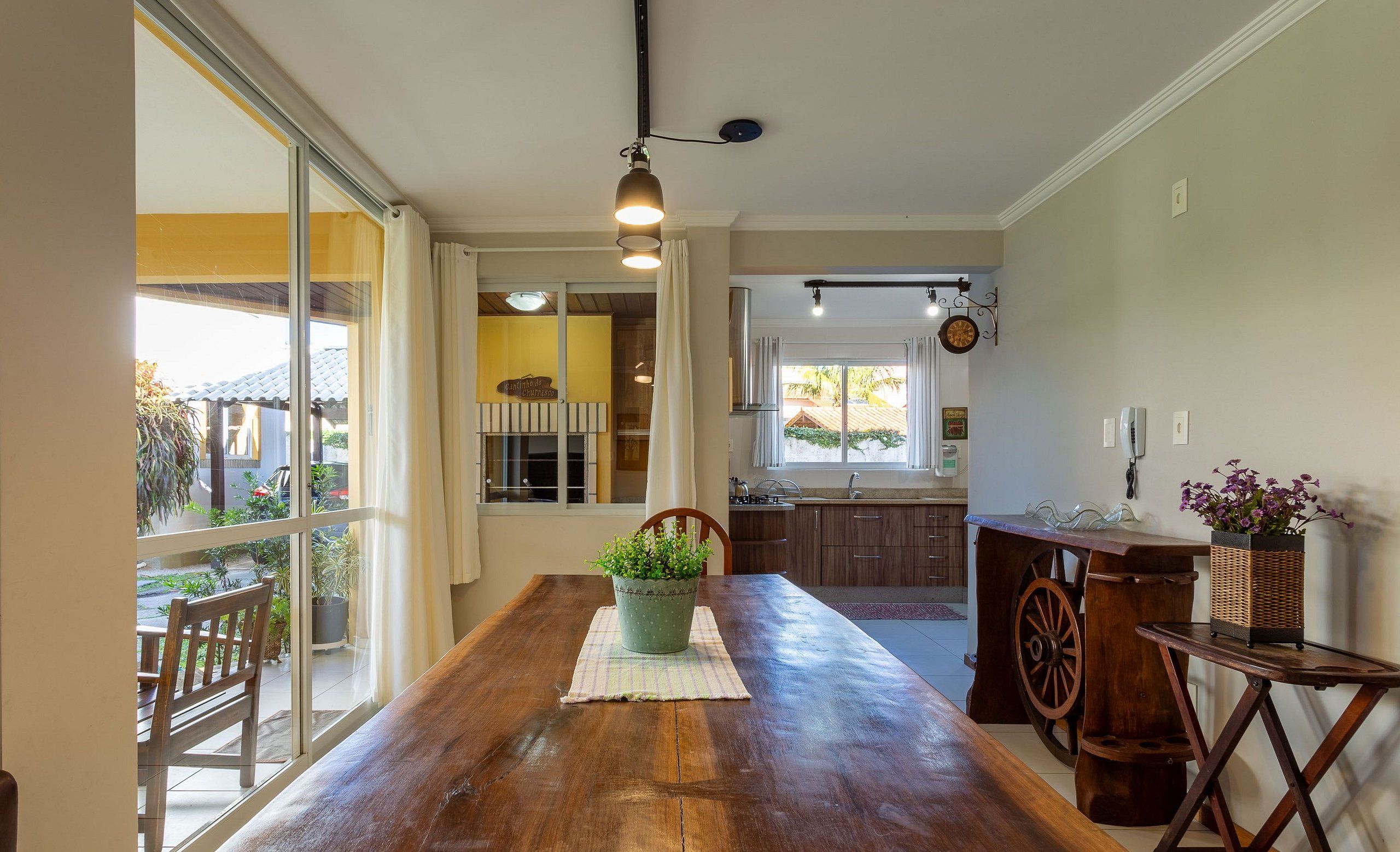 A spacious kitchen with a wooden table, a potted plant, and a large window.