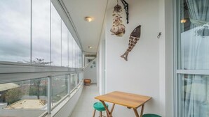 Un balcón con una mesa de madera y dos taburetes, un racimo de ajo colgando y una decoración de pez en la pared.
