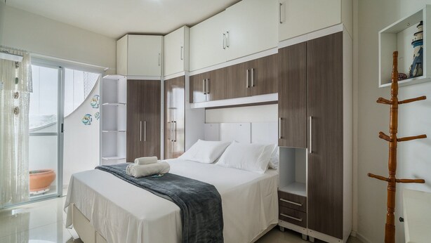 Un dormitorio con cama, armario y una pequeña estantería.