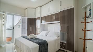 Un dormitorio con cama, armario y una pequeña estantería.